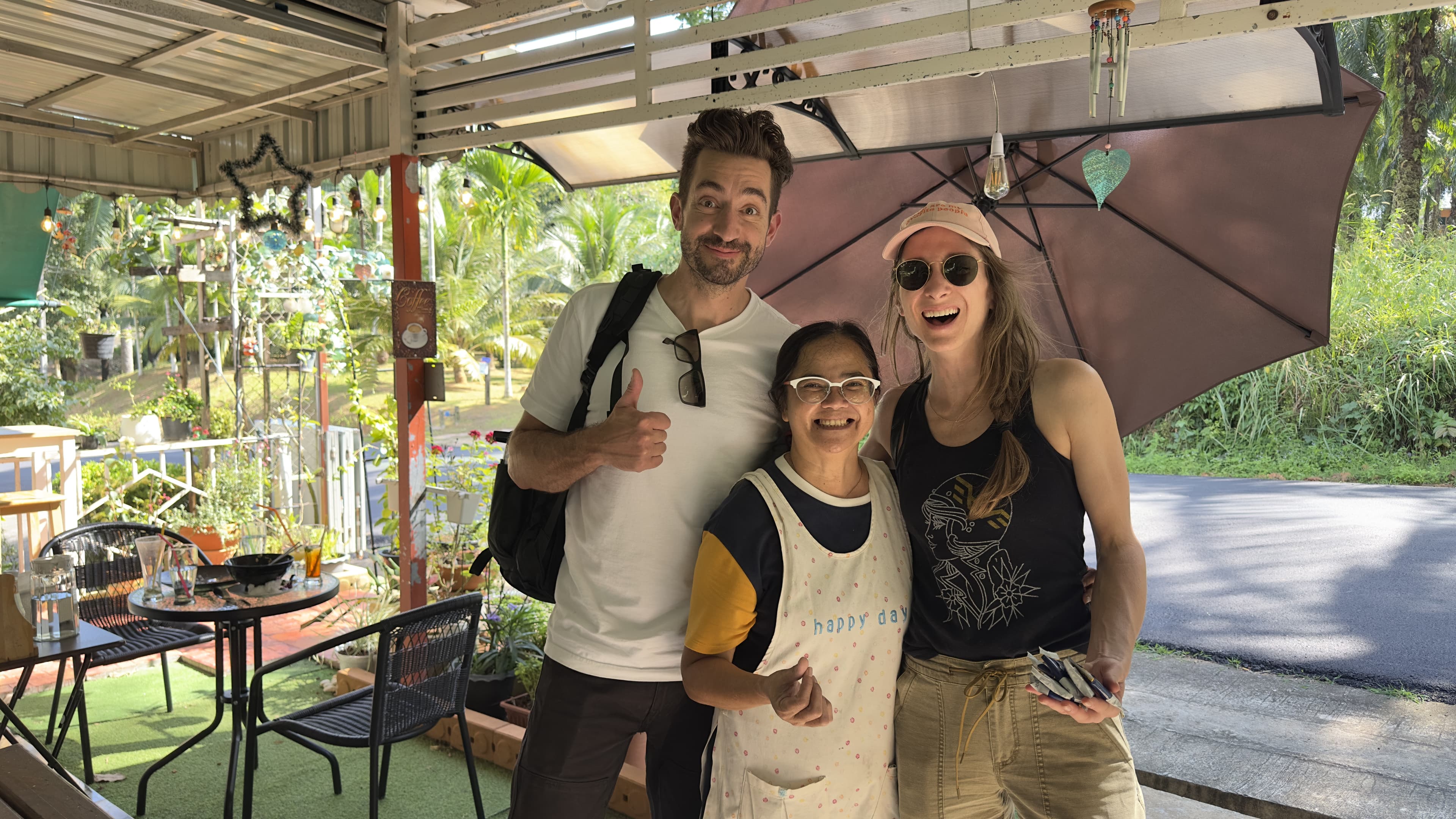 Owner smiling with happy international travelers outside MaeKung Cafe Krabi