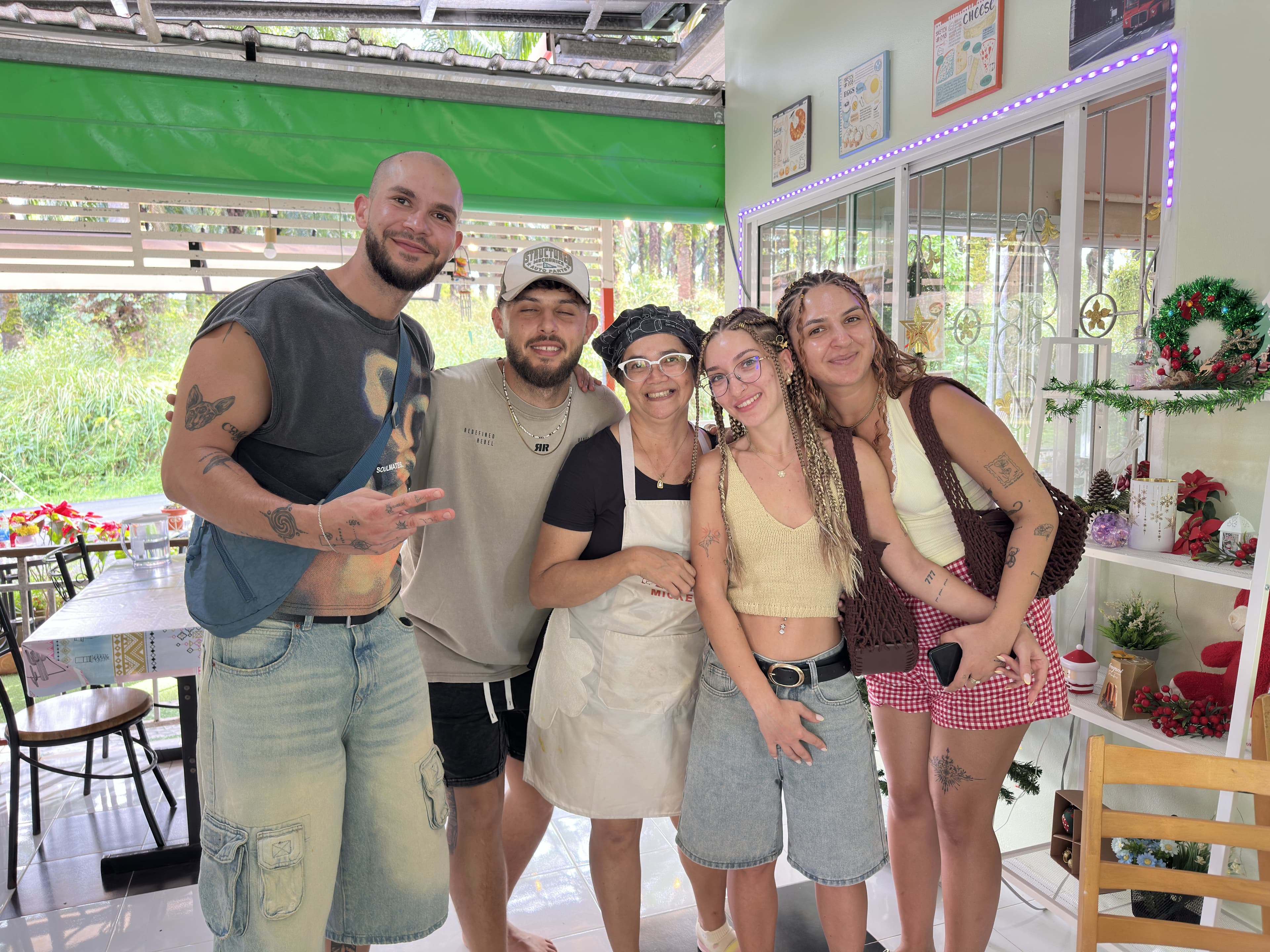 Owner posing with international guests at MaeKung Cafe Krabi