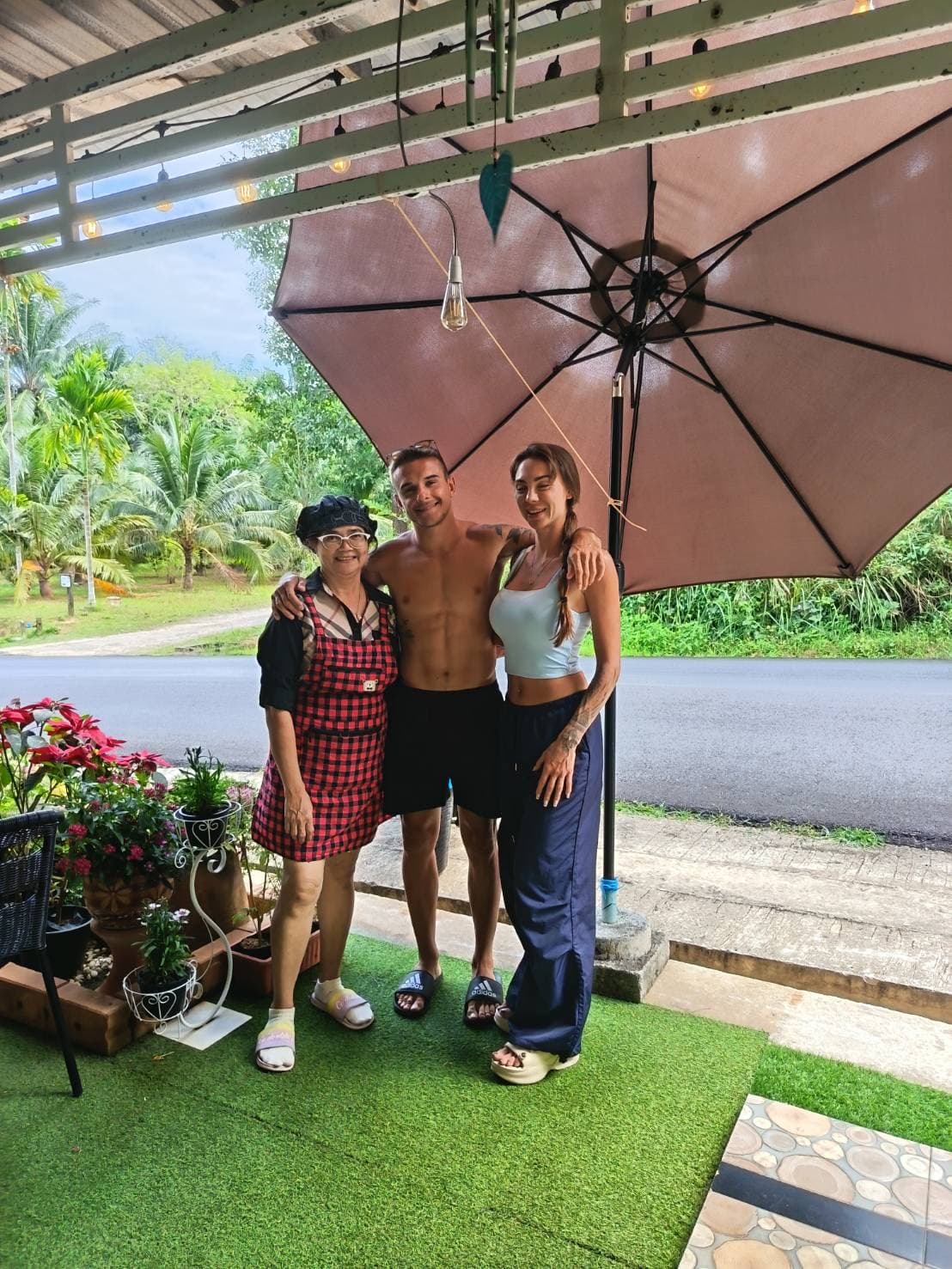 Owner with travelers in the tropical garden entrance of MaeKung Cafe Krabi